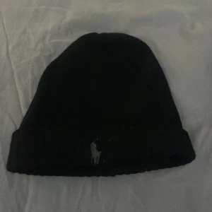 Polo Ralph Lauren mössa  - Snygg svart mössa från Polo Ralph Lauren med grå logga, storlek one size!