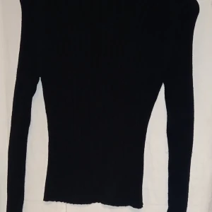 Svart ribbad tröja - Säljer en stilren svart ribbad tröja med lång ärm. Perfekt för kyligare dagar och lätt att matcha med olika outfits.