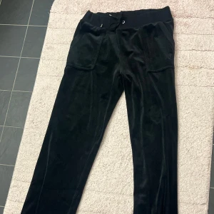 Svarta mjukisbyxor från juicy couture storlek M - Snygga svarta mjukisbyxor i mjukt material med broderad logga på sidan. Byxorna har en bekväm passform och dragsko i midjan för justerbarhet. Aldrig använda och jag köpte mjukisbyxorna från Nelly och jag köpte de för 1200 kronor men kan tänka mig att sälja för 700 kronor vid snabb affär och kan tänka mig att sänka priset. Storlek:M