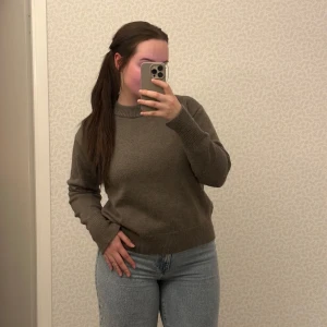 Grå/beige stickad tröja från H&M - Säljer en stilren grå/beige stickad tröja från H&M. Tröjan har en klassisk rund hals och långa ärmar med ribbade muddar. Perfekt för kyligare dagar och enkel att matcha med olika outfits.