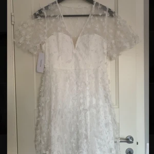 Vit blommig studentklänning från Bubbleroom - Säljer en vacker vit studentklänning från Bubbleroom med blommigt mönster, den kom inte till användning då jag hade en annan på studenten. Klänningen har en v-ringad design och är perfekt nu inför sommaren. Den är i storlek 38, jag är ungefär 165cm lång🥰 köpt för ungefär 1000kr, mitt pris 600kr💕