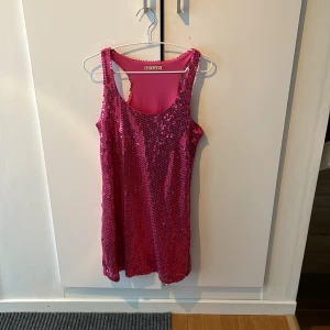 Rosa paljettklänning från ICHI - Snygg rosa klänning från ICHI täckt med glittriga paljetter. Perfekt för en festlig kväll. Klänningen är ärmlös och har en bekväm passform.