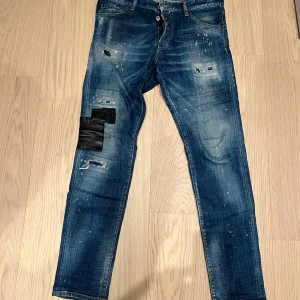 Blå jeans med slitningar och detaljer -  Blå Dsquared- jeans med coola slitningar och unika detaljer. Äkta och köpta på NK i Stockholm. Skick 7/10. Storlek 50.