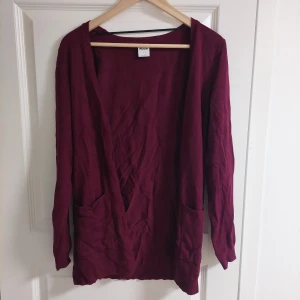 kofta från Vero Moda - Säljer en stilren vinröd kofta från Vero Moda. Koftan har långa ärmar och praktiska fickor framtill. Perfekt för att hålla sig varm under kyliga dagar. Passar bra till både vardag och mer avslappnade tillfällen. Är storlek L men passar även XL fint skick!