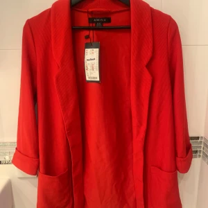 Röd kavaj från New Yorker - Snygg röd kavaj från New Yorker med långa ärmar och stilrena slag. Perfekt för att ge en färgklick till din outfit. Kavajen har praktiska fickor framtill och är tillverkad i ett bekvämt material.
