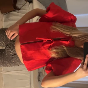 Röd kortärmad topp med knyt - Trendig röd topp med korta puffärmar och knyt framtill. Perfekt för en färgglad och stilren look.