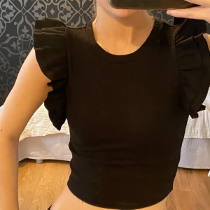 Topp med volangärmar - Svart topp med volangdetaljer på ärmarna🖤