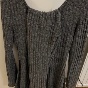 Grå ribbad mjukisar  - Snygg grå ribbad tröja med lång ärm med byxor. Perfekt för kyligare dagar med sin stickade look och bekväma passform. Slits vid sidorna av tröjan. 