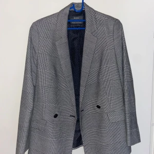 Grå rutig kavaj  - Snygg grå rutig kavaj med klassisk passform. Kavajen har två knappar framtill och fickdetaljer. Perfekt för en stilren look. Priset är inte hugget i sten