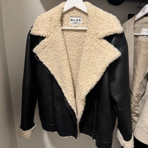 Svart skinnjacka med teddy - Snygg svart skinnjacka från NA-KD med beige/ vit teddyfoder. Den är lite oversized så skulle säga att storleken är som en normal S. 