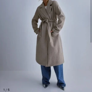 Beige kappa från Vero Moda - Snygg beige kappa från Vero Moda med knytbälte i midjan. Perfekt för höst och vår. Långärmad design med klassisk krage och rak passform i storlek XL! Aldrig använd men går ej att returns pga prislappen är av 🤍Köpt för 600kr, säljer 300kr
