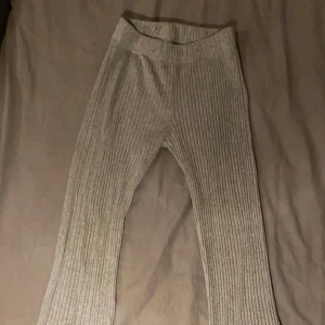 Grå ribbade byxor - Snygga grå ribbade byxor med hög midja och en bekväm passform. Perfekta för en avslappnad stil med en touch av elegans. Materialet är mjukt och stretchigt, vilket gör dem sköna att bära hela dagen.