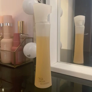 Pur Désir de Gardenia parfym - Elegant parfymflaska med en mjuk, böjd design och frostat glas. Innehåller en doft av gardenia som ger en fräsch och blommig känsla. Perfekt för den som älskar subtila och naturliga dofter.