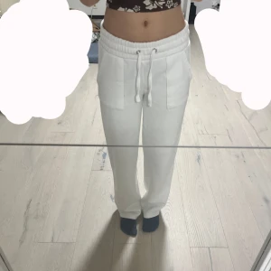 Vita mjukisbyxor med bakfickor  - Säljer ett par vita mjukisbyxor från 157 i storlek S. Byxorna har en bekväm elastisk midja med dragsko och praktiska fickor framtill. Perfekta för en avslappnad stil.