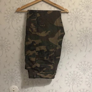 Camouflage cargopants - Snygga cargopants i klassiskt camouflagemönster. Byxorna har flera praktiska fickor och elastiska muddar vid bensluten för en bekväm passform. Perfekta för en avslappnad och cool stil.