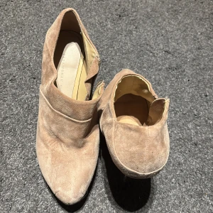 Beige mocka boots från Zara - Snygga beige boots i mocka från Zara med dragkedja på sidan. De har en spetsig tå och en stilren design som passar perfekt till olika tillfällen.