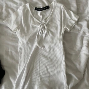 Vit ribbad topp från Lager 157 - Säljer en jätte gullig vit ribbad topp från lager 157. Toppen har korta ärmar och en knytning framtill vid halsen. Perfekt för en avslappnad och chic look.