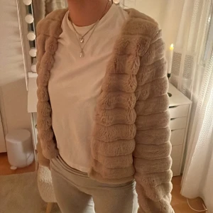 Beige pälsjacka från Gina Tricot - Säljer en supermjuk och fluffig beige pälsjacka från Gina Tricot. Jackan har en stilren design. Bra skick!