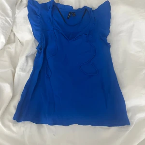 Blå blus från Vero Moda - Snygg blå blus från Vero Moda med volangdetaljer vid ärmarna och en v-ringad design. Perfekt för att lägga till en färgklick i garderoben. Använd ett fåtal gånger så super fint skick.💙