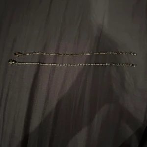Elegant armband - Säljer två stilrena och elegana armband från glitter. Ena armbandet har en tunn kedja med små glittrande stenar som ger en lyxig känsla. Det andra är en guldig kedja. Perfekt för att lägga till en touch av elegans till din outfit. Endast använda en gång på en bal. Från glitter. Kan köpas separat om så önskas.