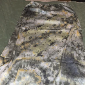 Mönstrad kjol från Erla - Säljer en unik mönstrad kjol från Erla i storlek S. Kjolen har ett abstrakt mönster i grått, gult och svart med en mjuk och glansig yta. 