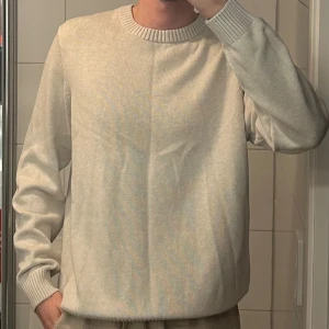 Beige stickad tröja dobber  - Säljer en stilren beige stickad tröja med rund halsringning och långa ärmar. Perfekt för kyligare dagar och enkel att matcha med olika outfits.