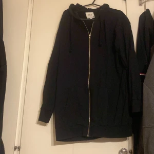 Svart hoodie från NEU - Säljer en svart hoodie från NEU i storlek M. Den har en dragkedja framtill och en bekväm huva med snörning. Perfekt för en avslappnad stil.