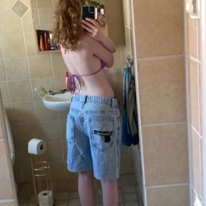 Jeansshorts med tryck - Säljer ett par coola jeansshorts i ljusblå denim med fransiga kanter. De har ett unikt tryck av en pistol och stjärna på bakfickorna som jag målat dit själv. 🙏🏻