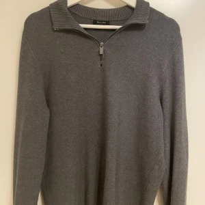 Grå quarter-zip från Massimo Dutti - Snygg grå tröja från Massimo Dutti med dragkedja och ribbad krage. Perfekt för kyligare dagar med sin stilrena design och bekväma passform. Storleken är M men sitter lite liten i storleken.
