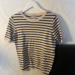 Randig tröja från H&M - Säljer en stilren randig tröja från H&M i beige och svart. Tröjan har korta ärmar och en rund halsringning med ribbade kanter. Perfekt för en avslappnad look.