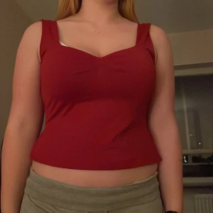 Röd ärmlös topp - Snygg röd ärmlös topp med en stilren design. Toppen har en v-ringad framdel och en bekväm passform. Perfekt för en kväll ute eller en avslappnad dag.