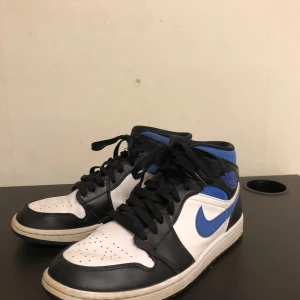 Nike Air Jordans i svart, vit och blå - Snygga Nike Air Jordans i svart, vit och blå med klassisk snörning. Perfekta för dig som vill ha en stilren och sportig look.