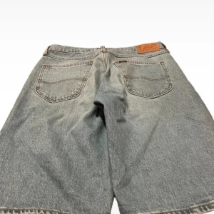 Blå jeansshorts från Lee - Snygga blå jeansshorts från Lee med klassisk femficksdesign. Perfekta för en avslappnad stil. De har en knappgylf och en läderpatch med Lee-loggan baktill. Perfekta för sommardagar! Storlek s