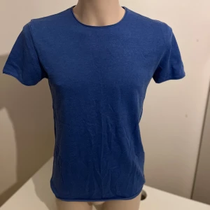 Blå stickad t-shirt från Zara Man - Snygg blå stickad t-shirt från Zara Man i mjukt material. Perfekt för en avslappnad stil. Den har en klassisk rund hals och korta ärmar.