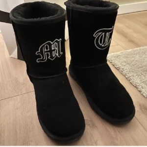 Svarta boots med broderad bokstav - Snygga svarta boots med broderade bokstäver i vitt. De har en mjuk insida och är perfekta för kyligare dagar. Stilren design som passar till många olika outfits.