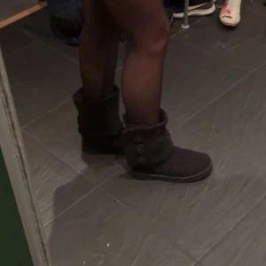 Svarta stickade boots från UGG Stövlar / UGG Classic Cardy Boot / Svarta skor / storlek 38 - Säljer ett par svarta stickade boots från UGG med knappar på sidan. De har en mjuk och bekväm sula, perfekt för kyligare dagar. Stövlarna är både stiliga och praktiska med en unik design.