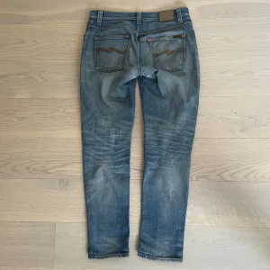 Nudie Jeans Grim tim - Snygga nudie jeans i modellen Grim tim. Skicket är bra men minimala defekter förekommer. Små hål i skrevet, när de är på syns det ej. 32/34