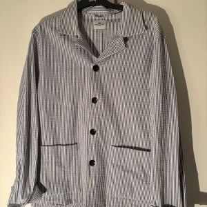 Randig skjorta från John Henric - Snygg randig skjorta från John Henric i blått och vitt. Skjortan har långa ärmar och knappar framtill. Perfekt för en stilren look.