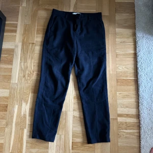 Blåa  kostymbyxor från Les Deux - Snygga svarta byxor från Les Deux med en stilren design. Byxorna har en klassisk passform och är perfekta för en stilren look. De är tillverkade i ett mjukt material som ger en bekväm känsla hela dagen.