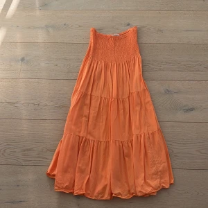 Orange kjol från Cosy House - Säljer en härlig orange kjol från Cosy House. Kjolen har en smockad överdel och ett luftigt fall som ger en skön känsla. Perfekt för varma dagar och somriga äventyr. 🧡