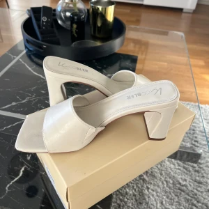 Off-white klackskor från K.Cobler - Snygga off-white klackar från K.Cobler med öppen tå och bred rem. Klackarna har en bekväm klack och är perfekta för sommarens alla tillfällen. Stilren design som passar till många olika outfits. Använd en gång 💛