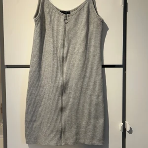 Grå ribbad klänning från Bershka - Snygg grå ribbad klänning från Bershka med dragkedja. Klänningen är ärmlös och har en enkel design.
