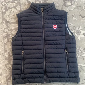 Mörkblå dunväst från Colmar - Snygg mörkblå väst från Colmar med dragkedja och två praktiska fickor framtill. Västen har en stilren design med Colmar logga på bröstet. Perfekt för lite kyligare dagar.