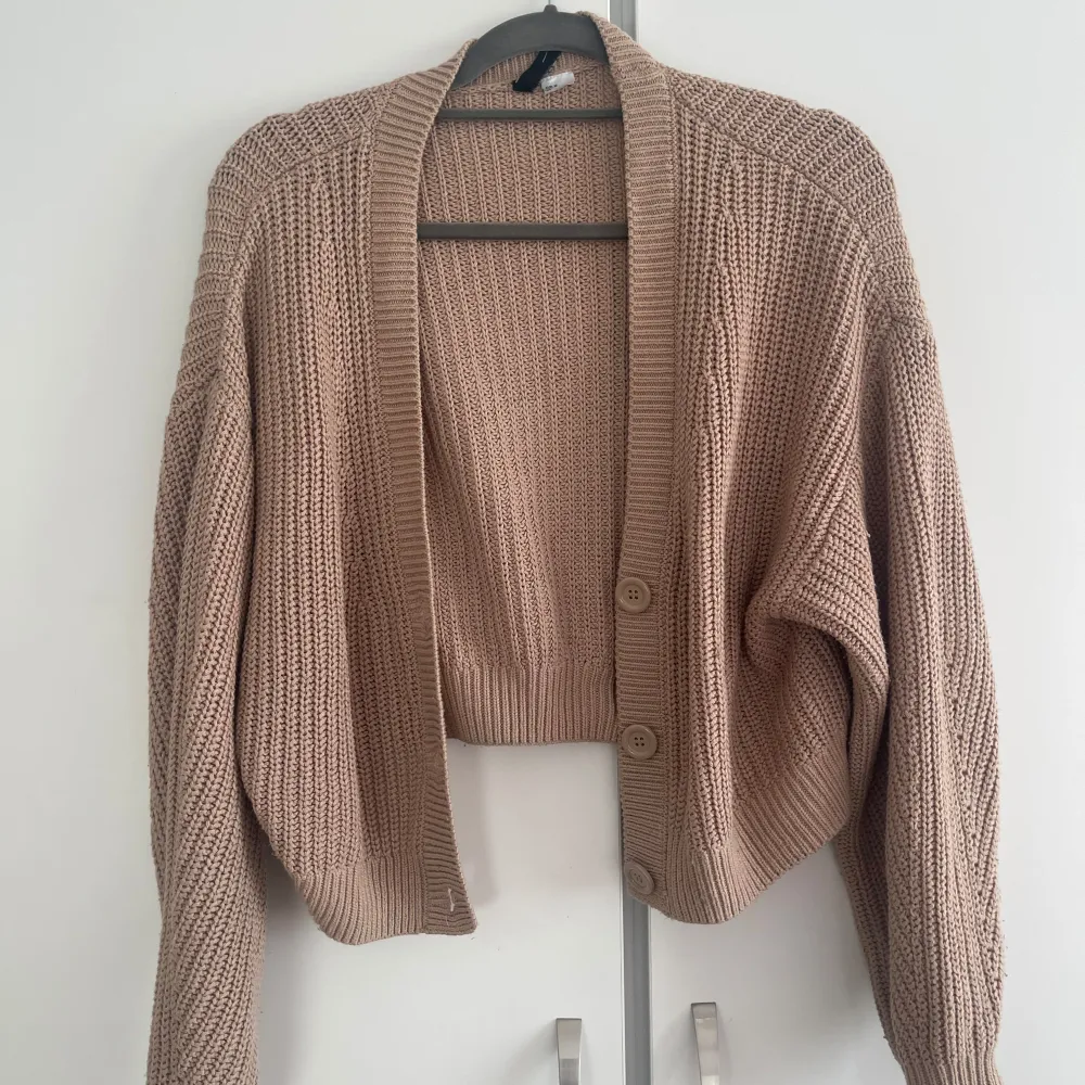 Säljer en mysig beige stickad kofta med knappar framtill. Koftan har en lös passform och långa ärmar, perfekt för kyliga dagar. Den är både stilren och bekväm.. Neuletakit & Villapaidat.