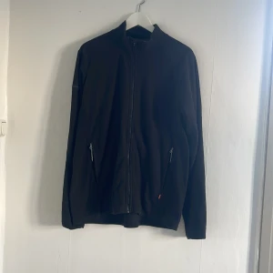 Svart fleecejacka från Didriksons - Säljer en svart fleecejacka från Didriksons i storlek XL. Jackan har en dragkedja framtill och två praktiska fickor med dragkedjor. Perfekt för kyligare dagar med sin mjuka och varma polyesterkonstruktion.