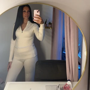 Vit ribbad tröja med dragkedja - Säljer en stilren vit ribbad tröja med dragkedja framtill. Tröjan har långa ärmar och en bekväm passform, perfekt för en avslappnad look. Passar bra till både jeans och mjukisbyxor.