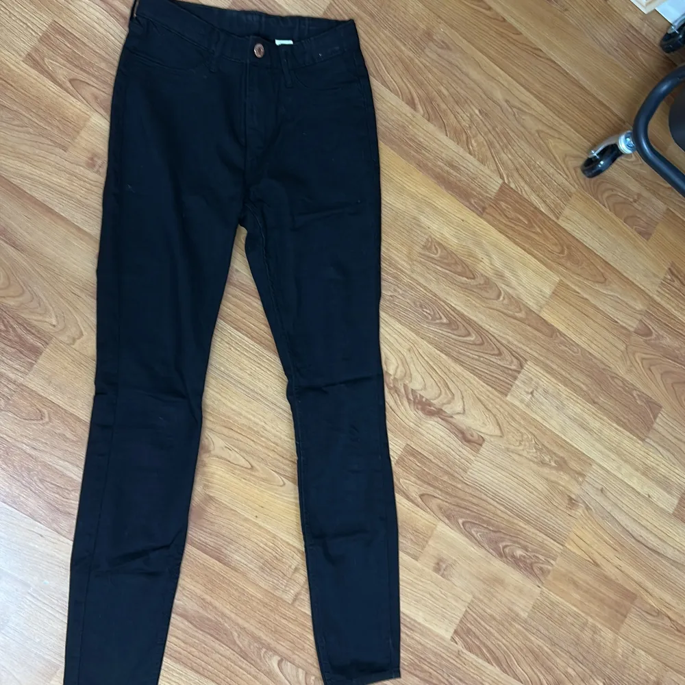 Snygga svarta jeansbyxor med en tight passform. De har en klassisk design med knapp och dragkedja framtill. Perfekta för en stilren look.. Farkut & Housut.