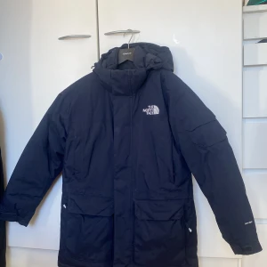 Svart parkajacka från The North Face - Säljer en stilren mörkblå parkajacka från The North Face. Jackan har en långärmad design med huva och praktiska fickor framtill. Perfekt för kyligare dagar med sin robusta och funktionella stil. 🖤. Bra skick, knappt använd och mycket varm. 