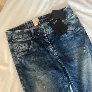 Jättesnygga jeans från Soulmate - Hej! Jag säljer ett var jättesnygga jeans från soulmate då de var för små för mig. Baksidan av jeansen har en fin detalj samt fickorna. Jeansen har en cool look genom dess blommor vid midjan, lite skräpiga hål (se bild) samt backsidan. Midjemått: 37 cm, innebenslängd: 81. (Lappen är kvar med detaljer om jeansen men priset fanns inte kvar vid köp)