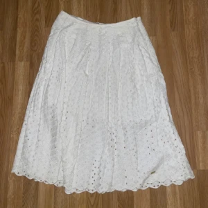 Vit  långkjol - Charmig vit långkjol . Kjolen har en luftig och elegant design. Perfekt för en somrig look.